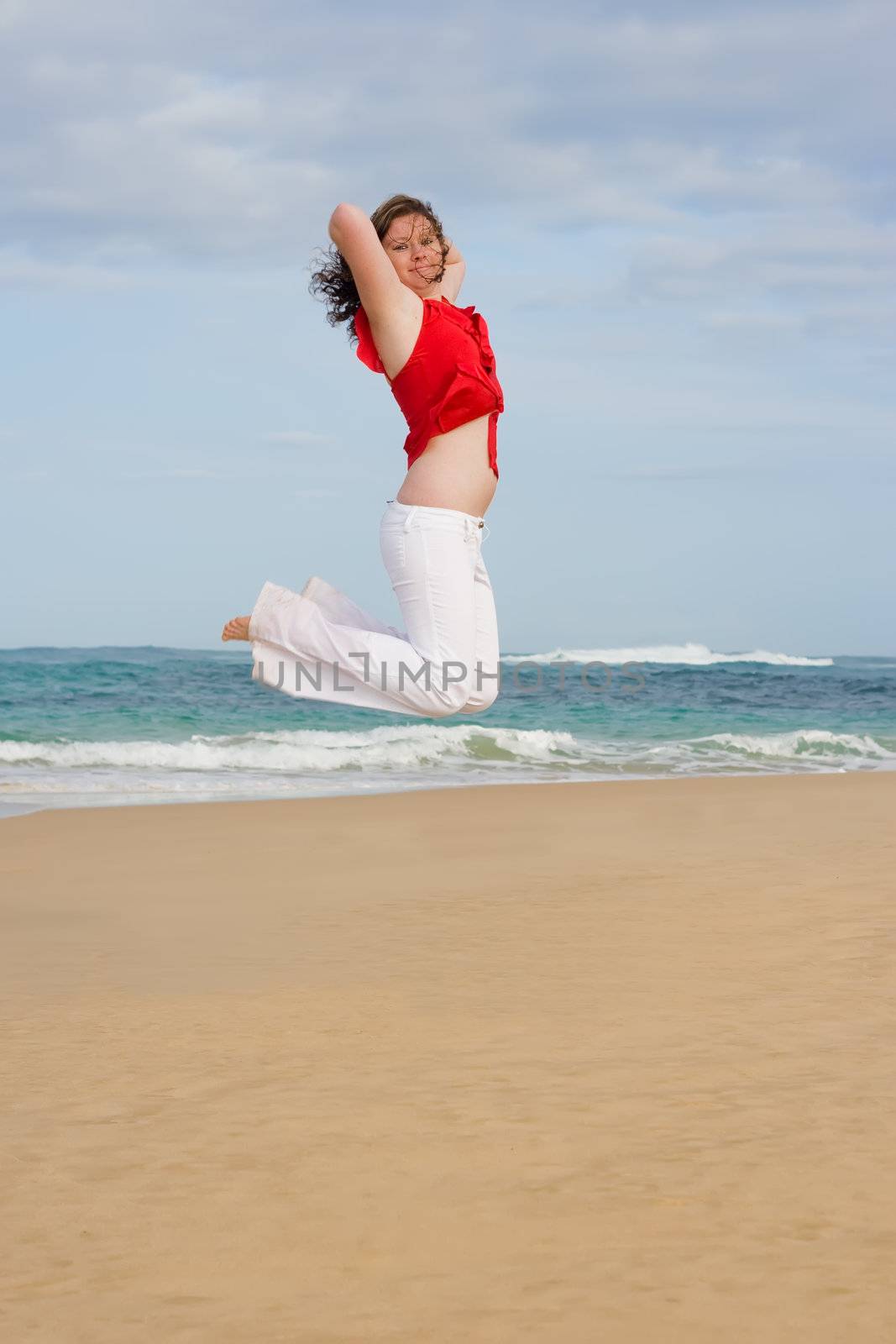 Jumping for joy on the beach wearing red and white