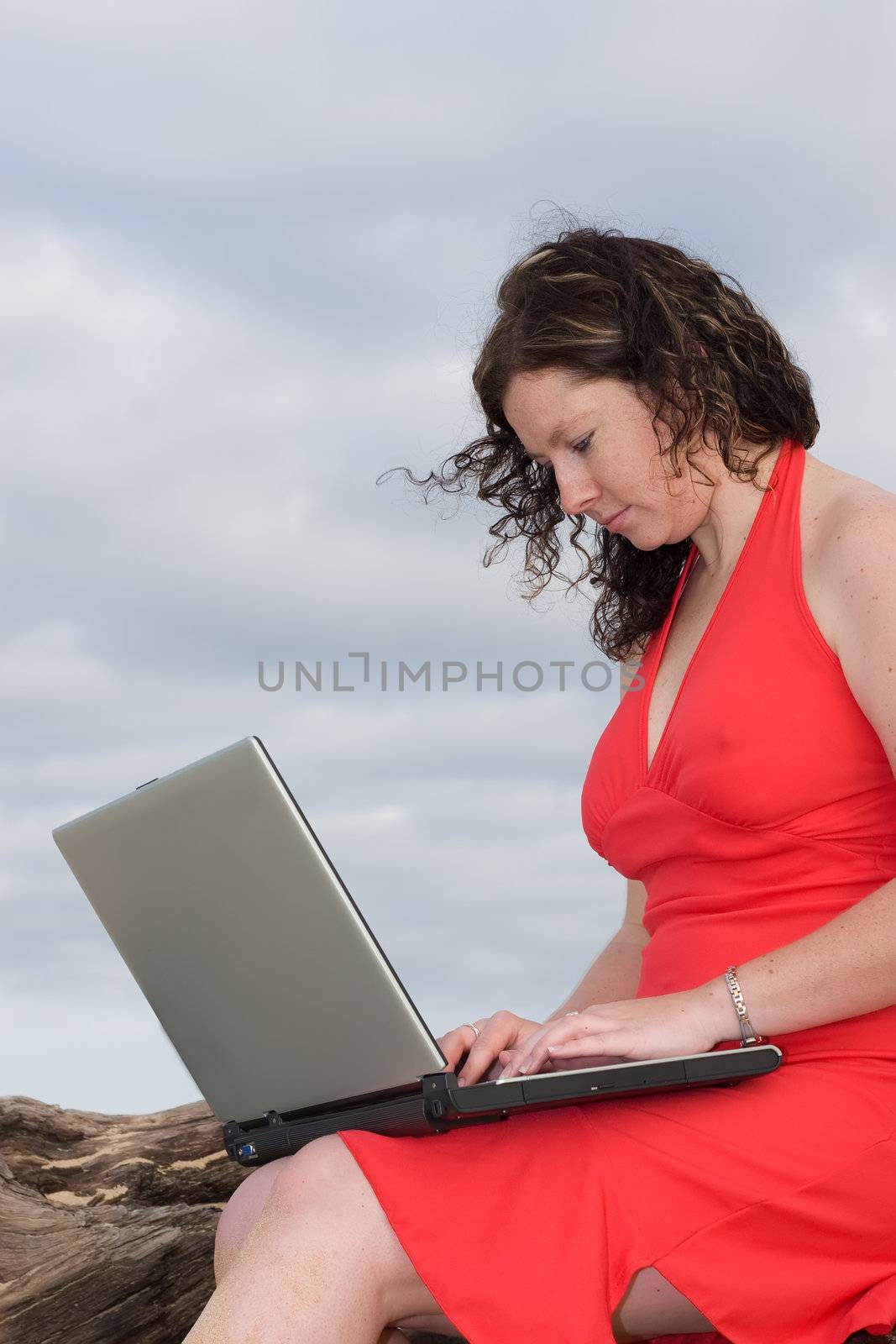 Lady in red dress typing on a laptop