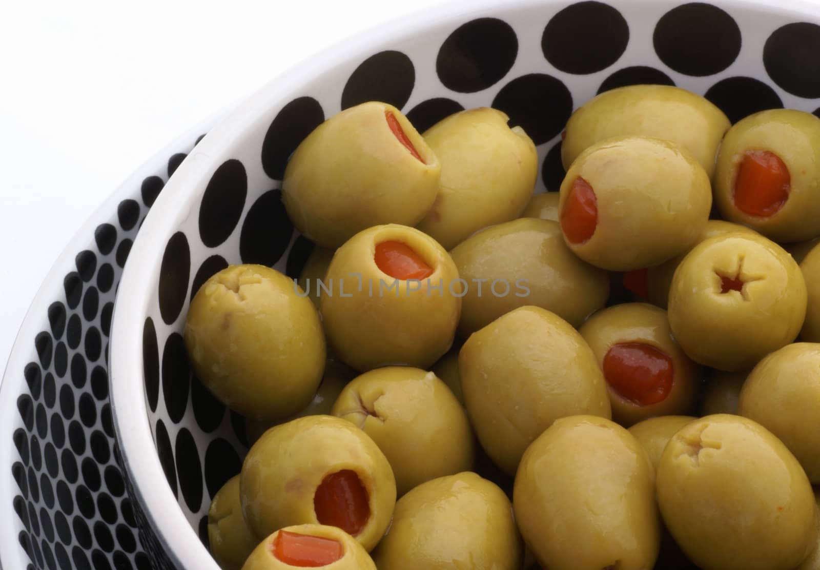 Greenstuffed olives in black and white bowls.