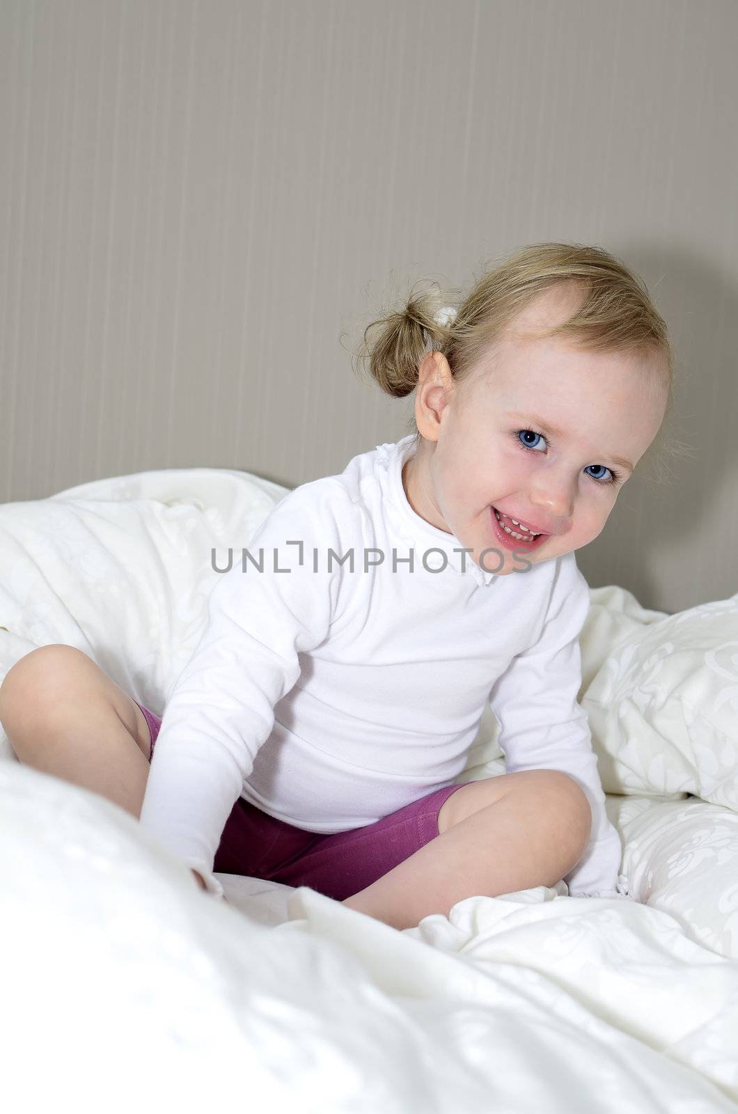 little girl sitting on a bed and smiling