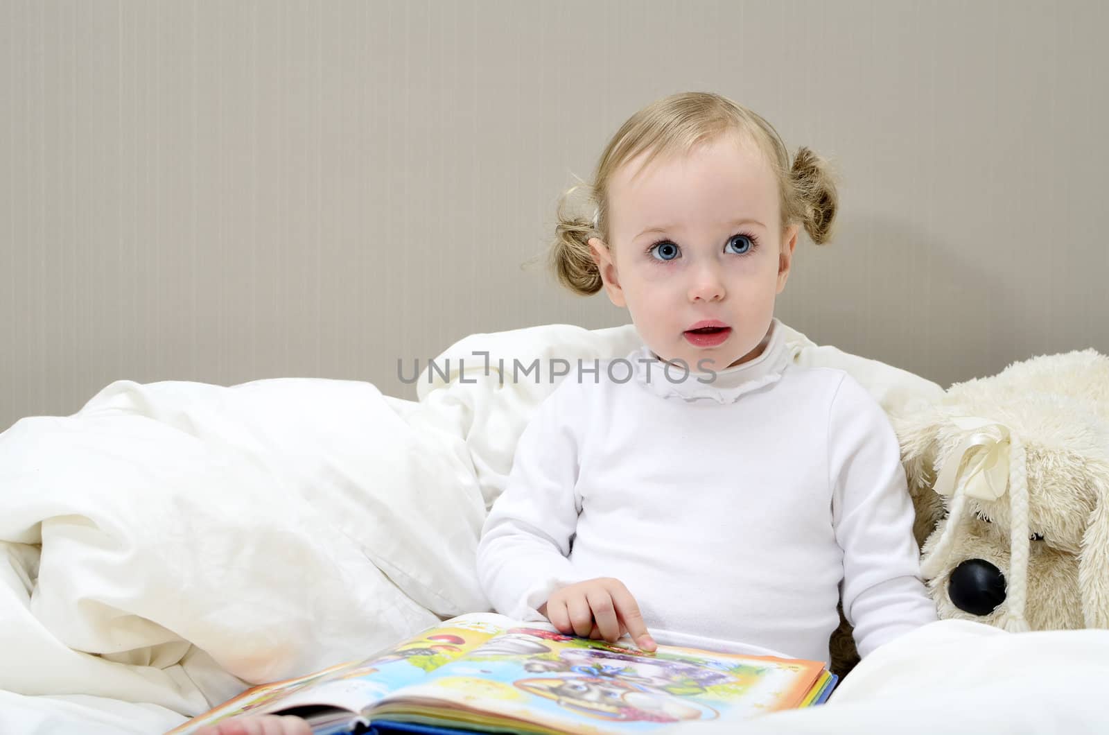 little girl sitting on the bed and reading a book