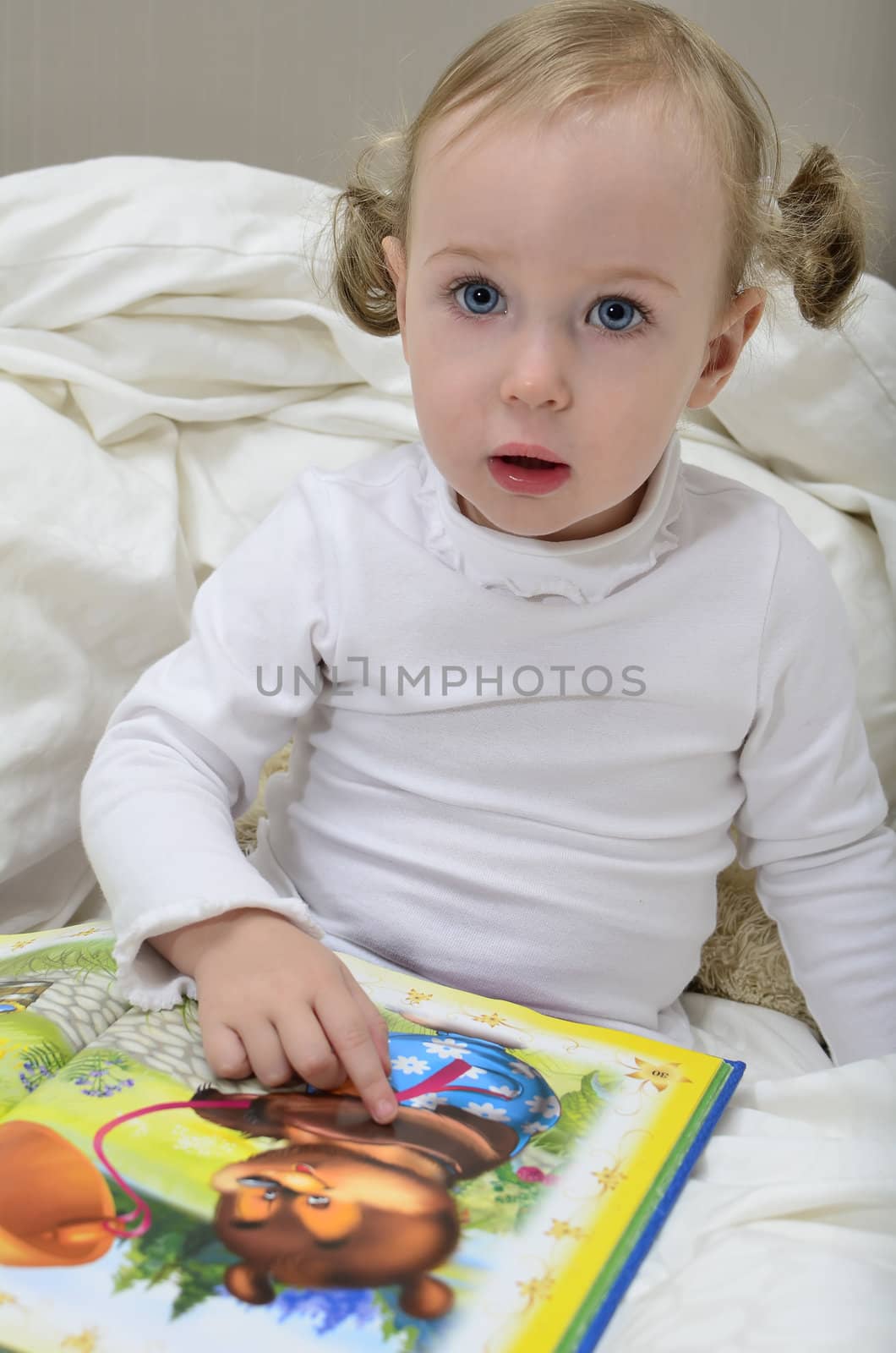 little girl sitting on the bed and reading a book
