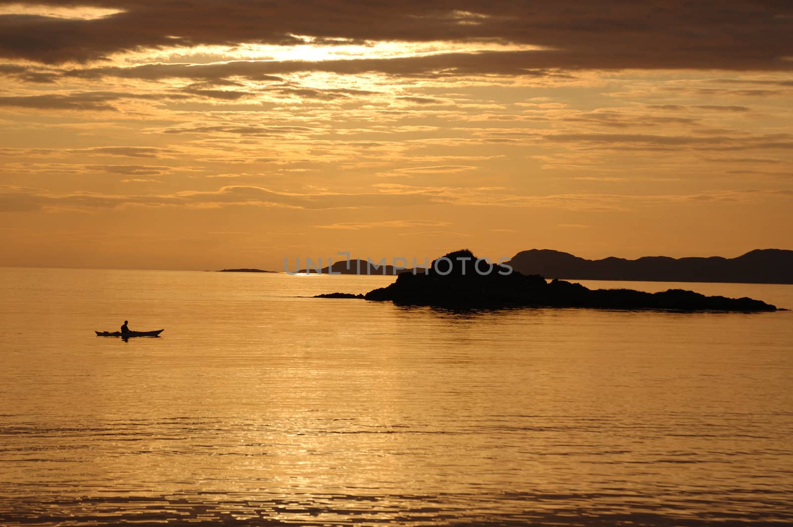 A lone canoeist at sunset from the shoreline at Arisaig, Scotland