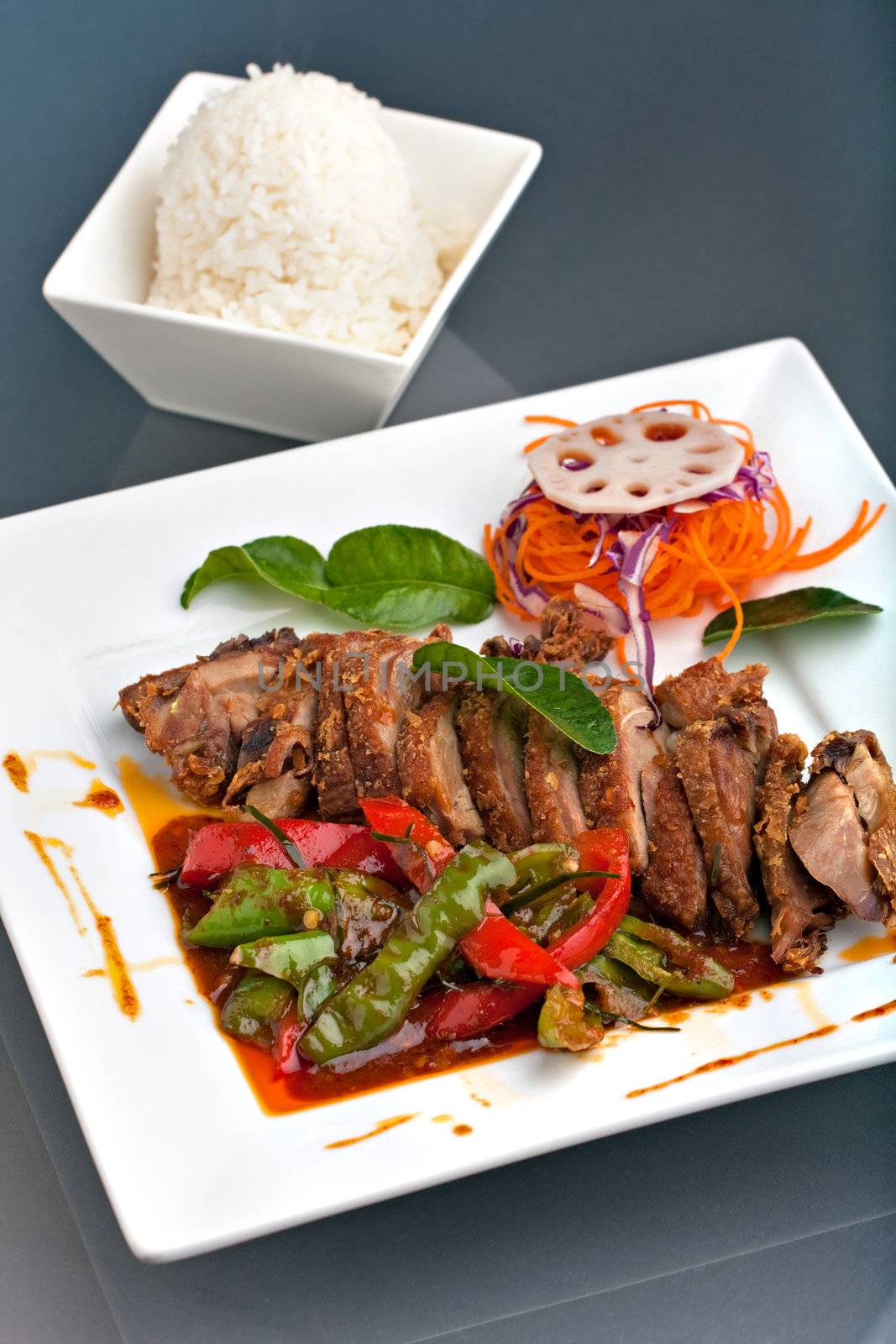 A fresh dish of Thai style roast chile basil duck with mixed vegetables white jasmine sticky rice.