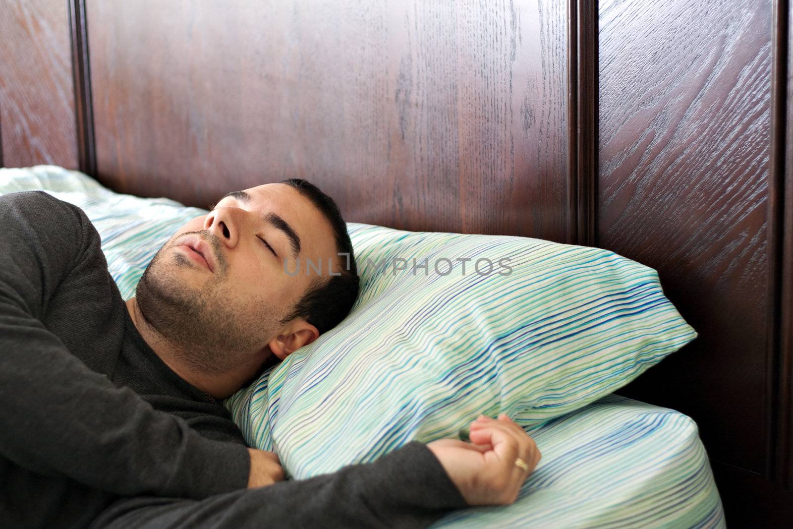 A man in his late 20s is fast asleep in bed.