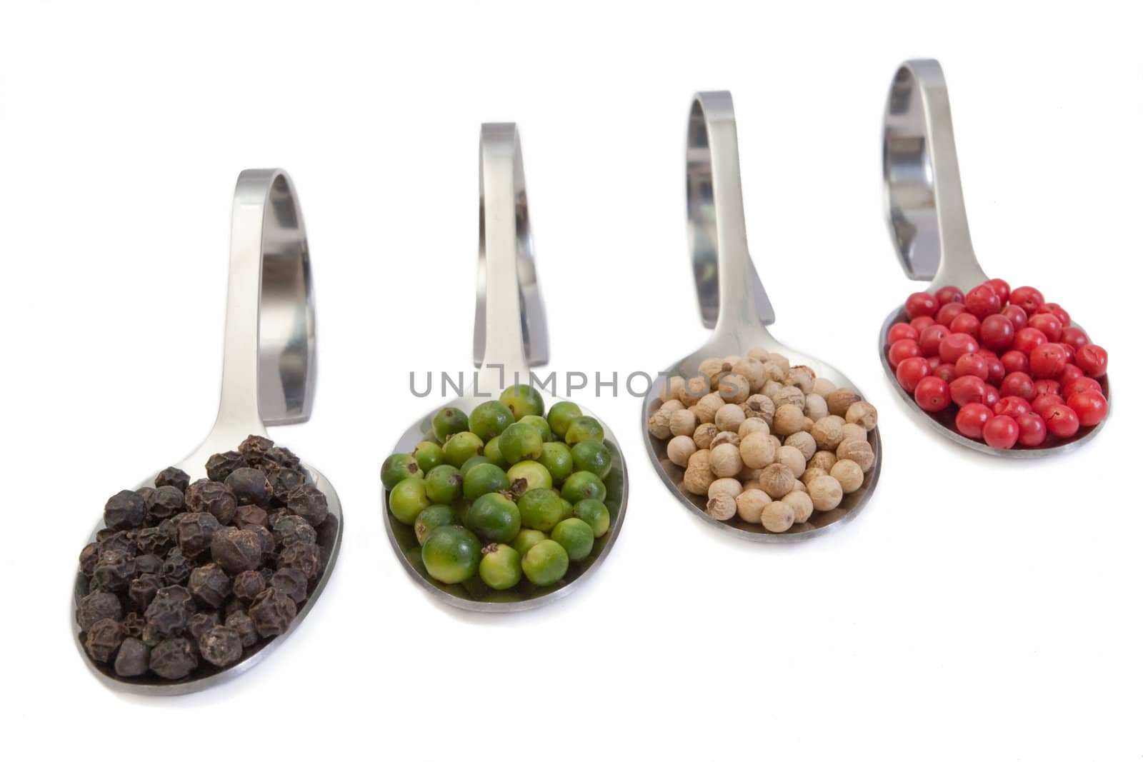 Four kinds of peppercorns in spoons isolated on white background