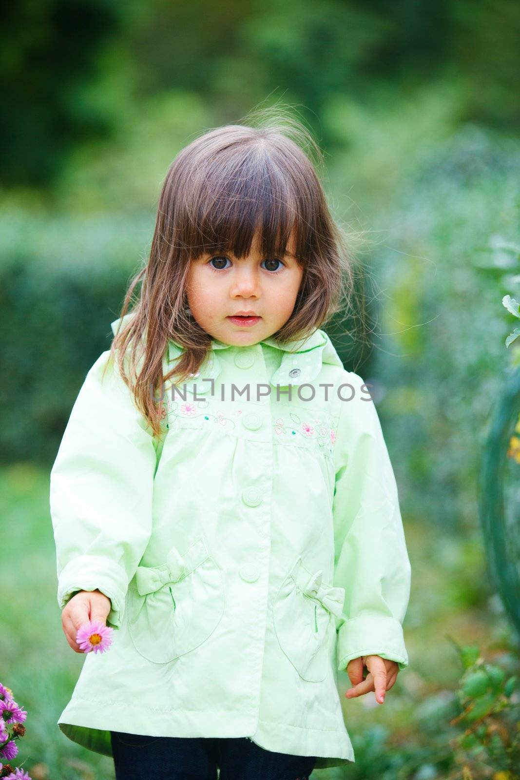 Clouse-up portrait pretty little girl in the park with a flower
