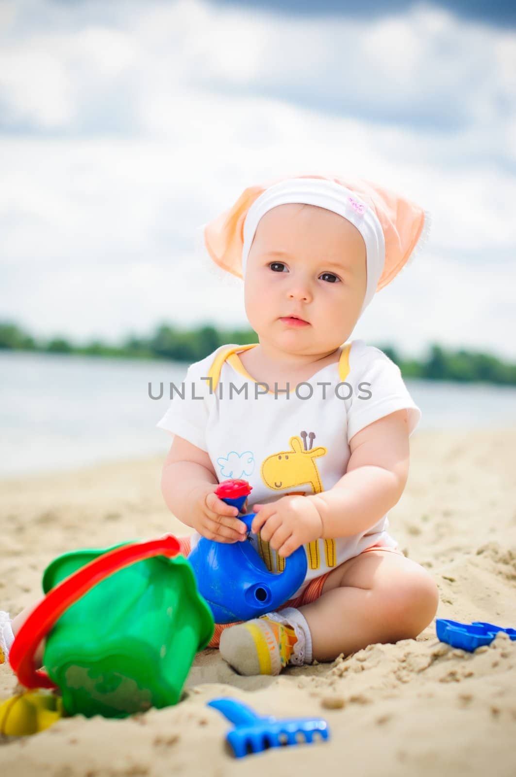 cute baby girl playing on the beach with sand. Vertical view