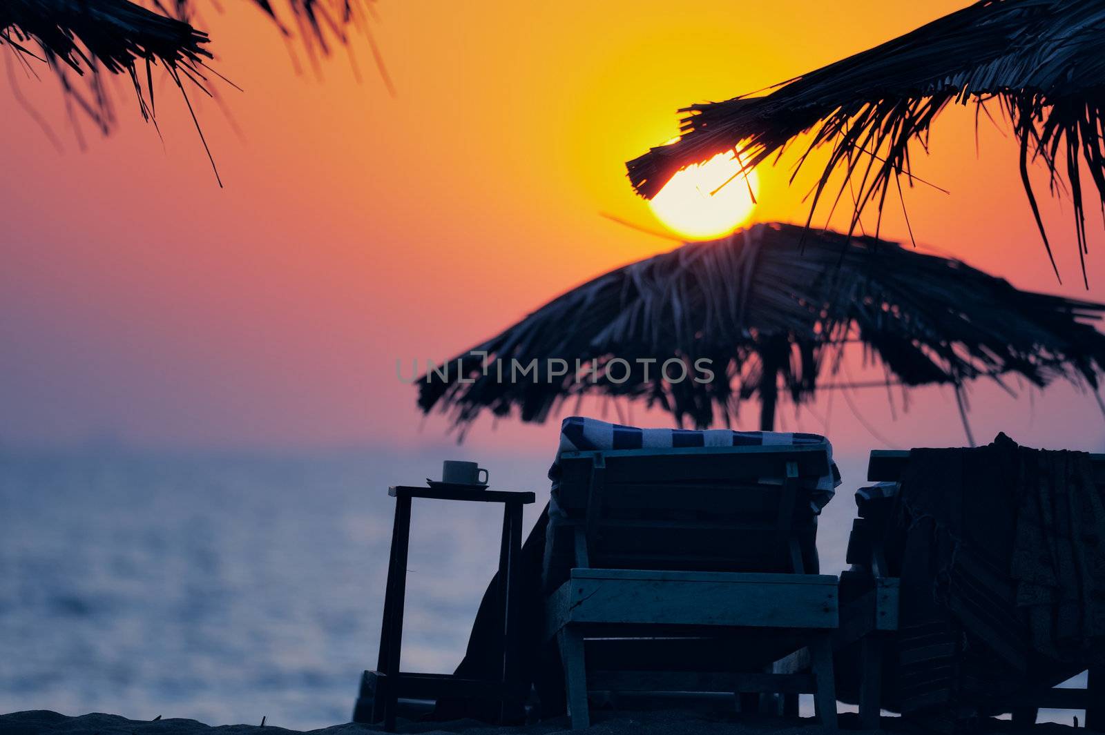 Exotic beach umbrellas and chairs on tropical coast on evening