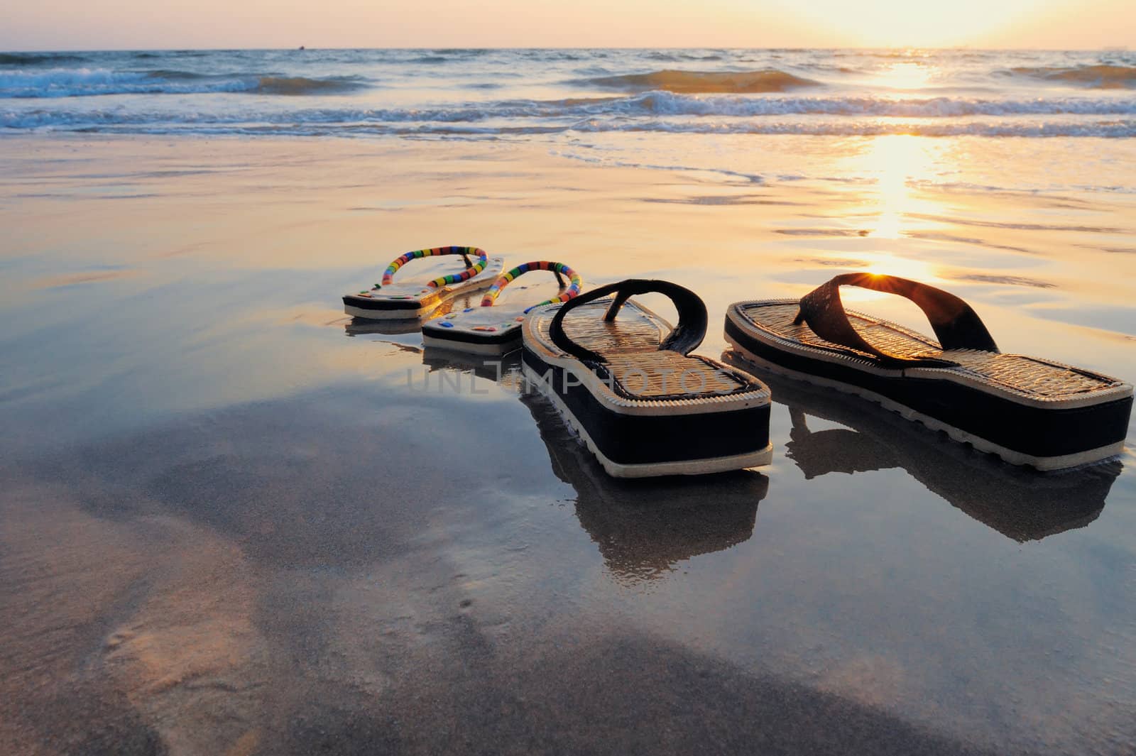 Beach sandals on the wet sandy shore