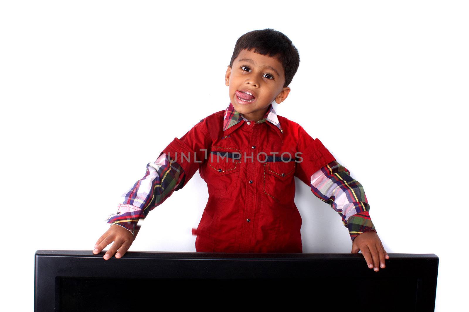 A cute Indian boy fooling around his television set.