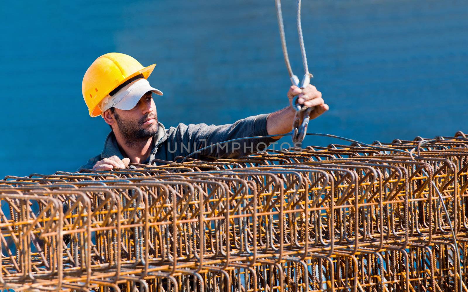 Authentic construction worker loading steel reinforcement stirrup beam cages to a crane hook