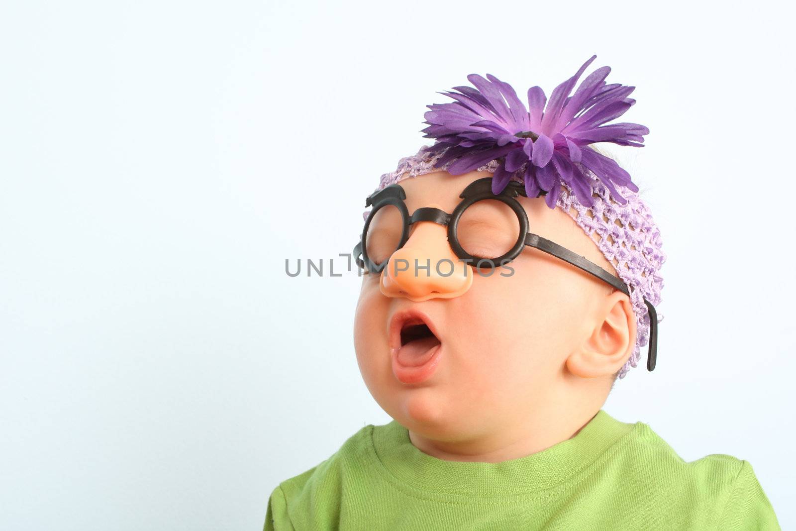 Funny baby wearing toy glasses and headband