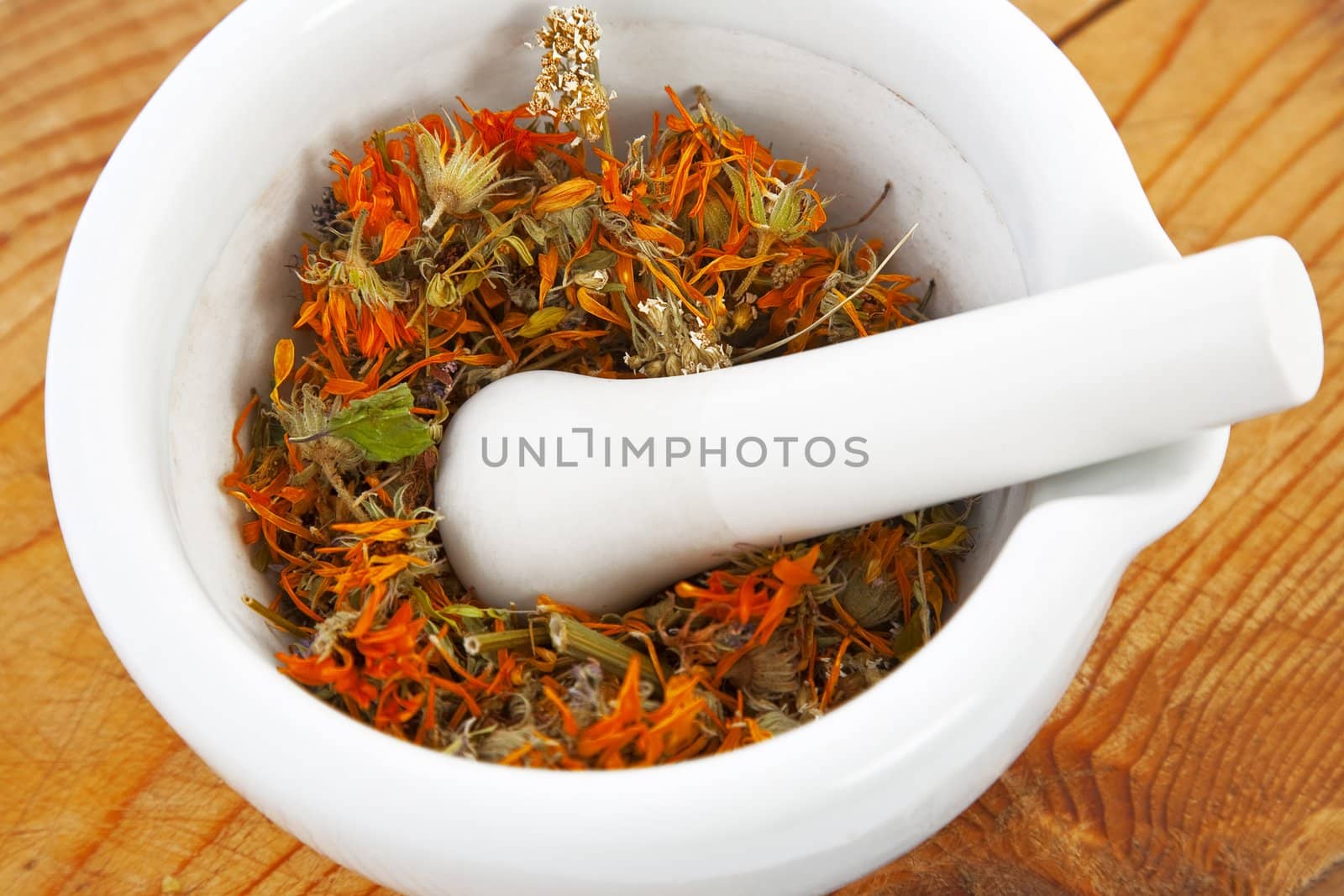 white mortar with dry marigold flower on wooden background