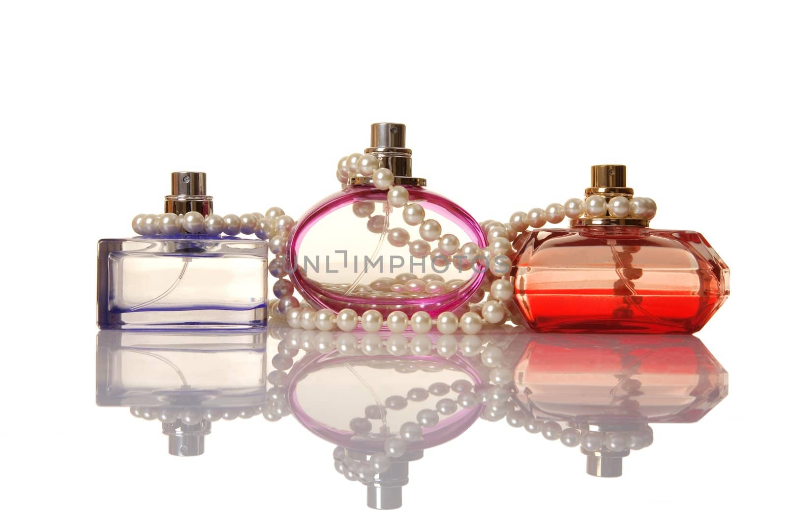 Perfume in a glass bottles and pearl beeds on white background