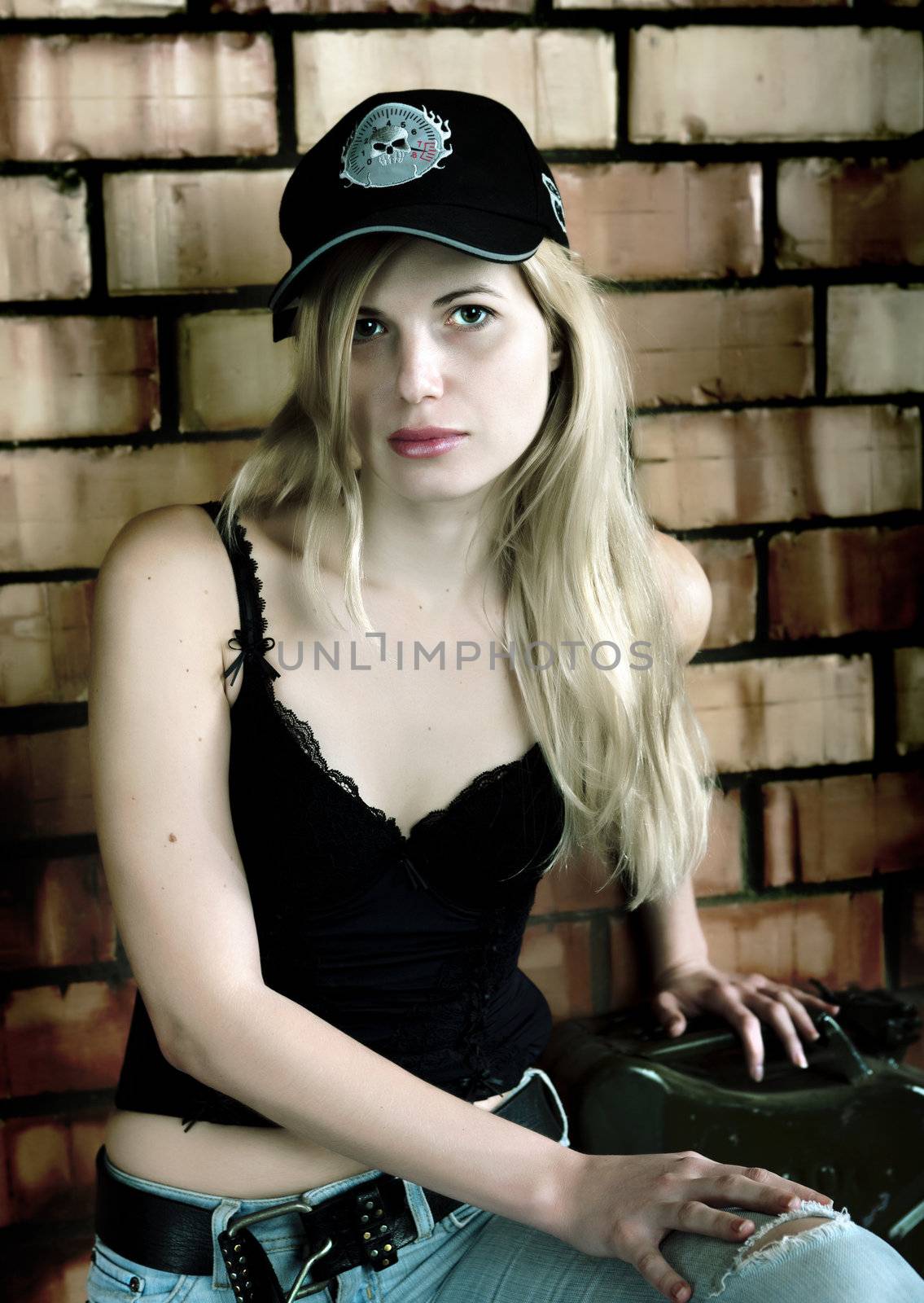 Sexy blonde on the background of a brick wall. A young woman in the garage.