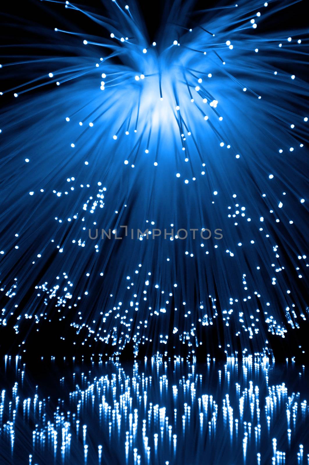 Many illuminated blue fiber optic light strands cascading down and reflecting into the foreground. Black background
