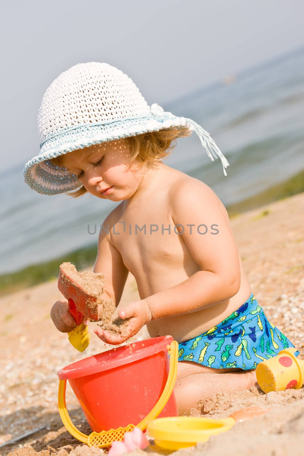 little girl in the bonnet playing with sand