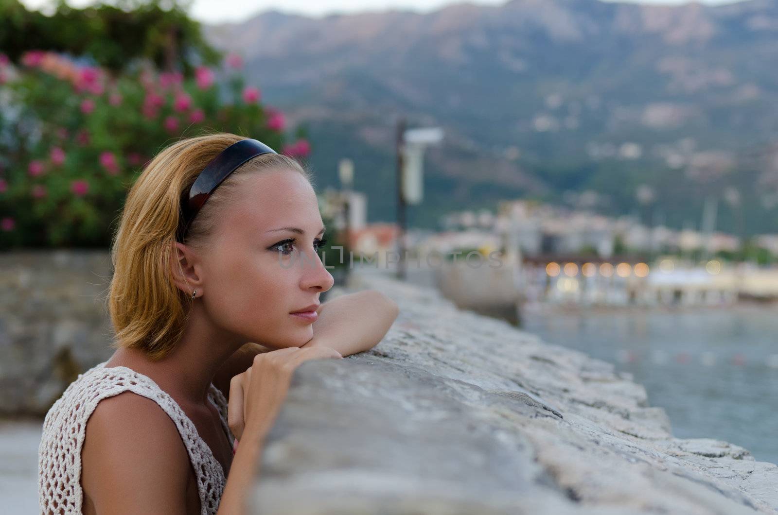 Young pensive woman looking at the sunset over the sea