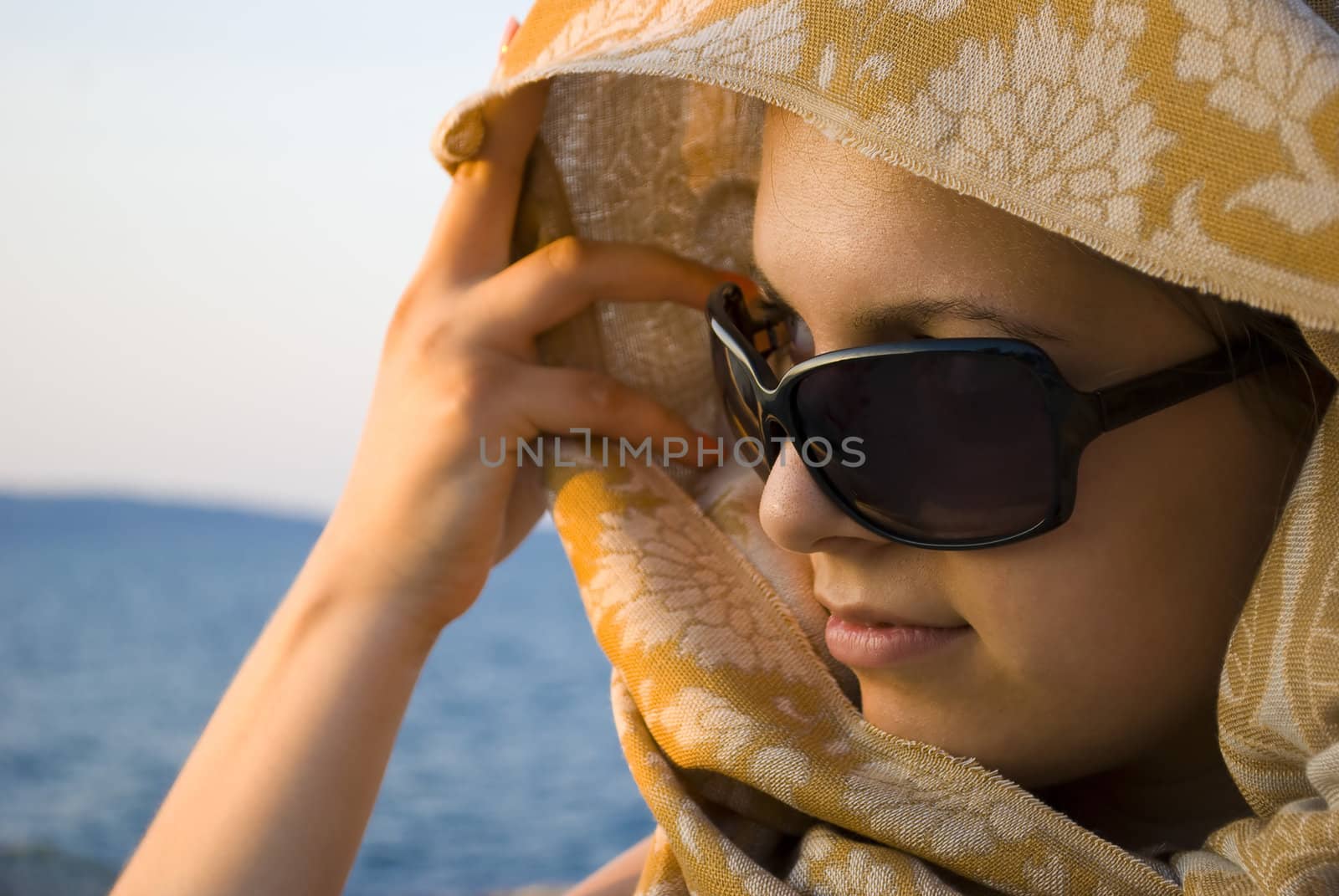 beautiful young woman posing with scarf on sunset near sea