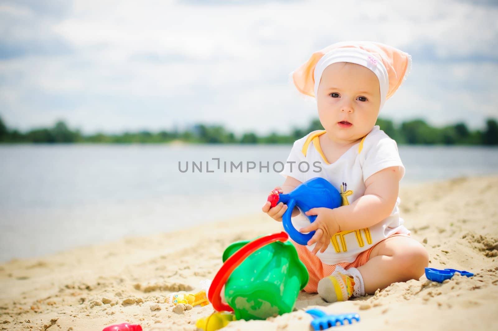 cute baby girl playing on the beach with sand.