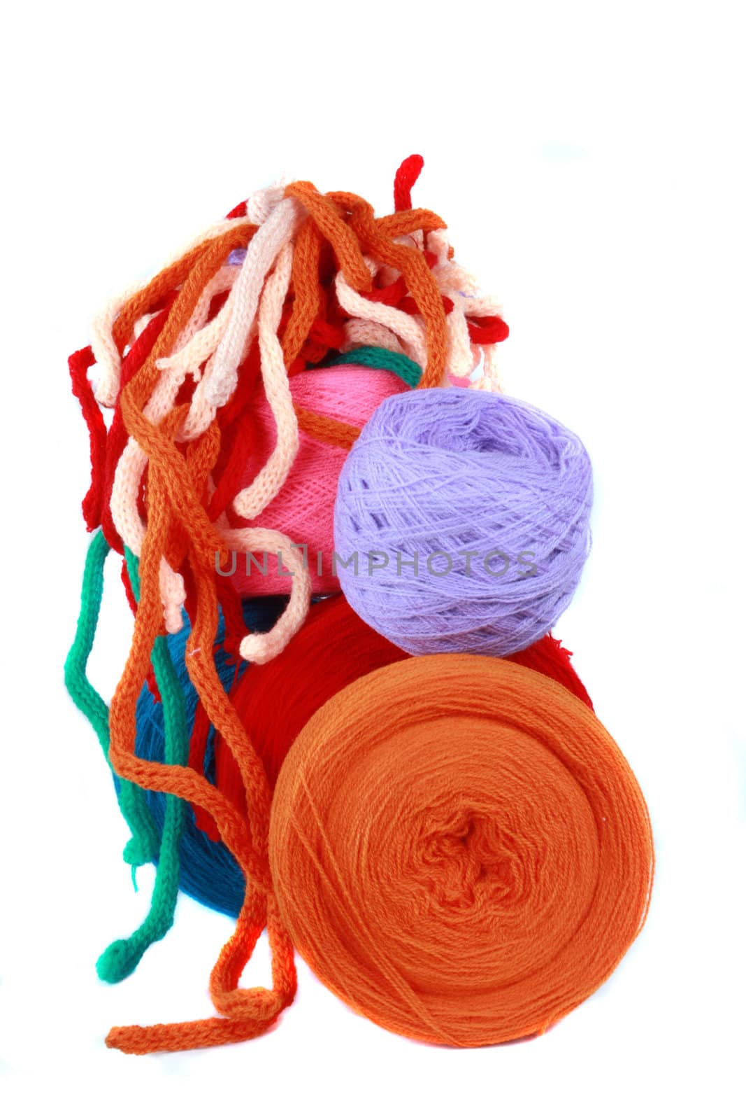 Balls and threads of colorful wool, on white studio background.