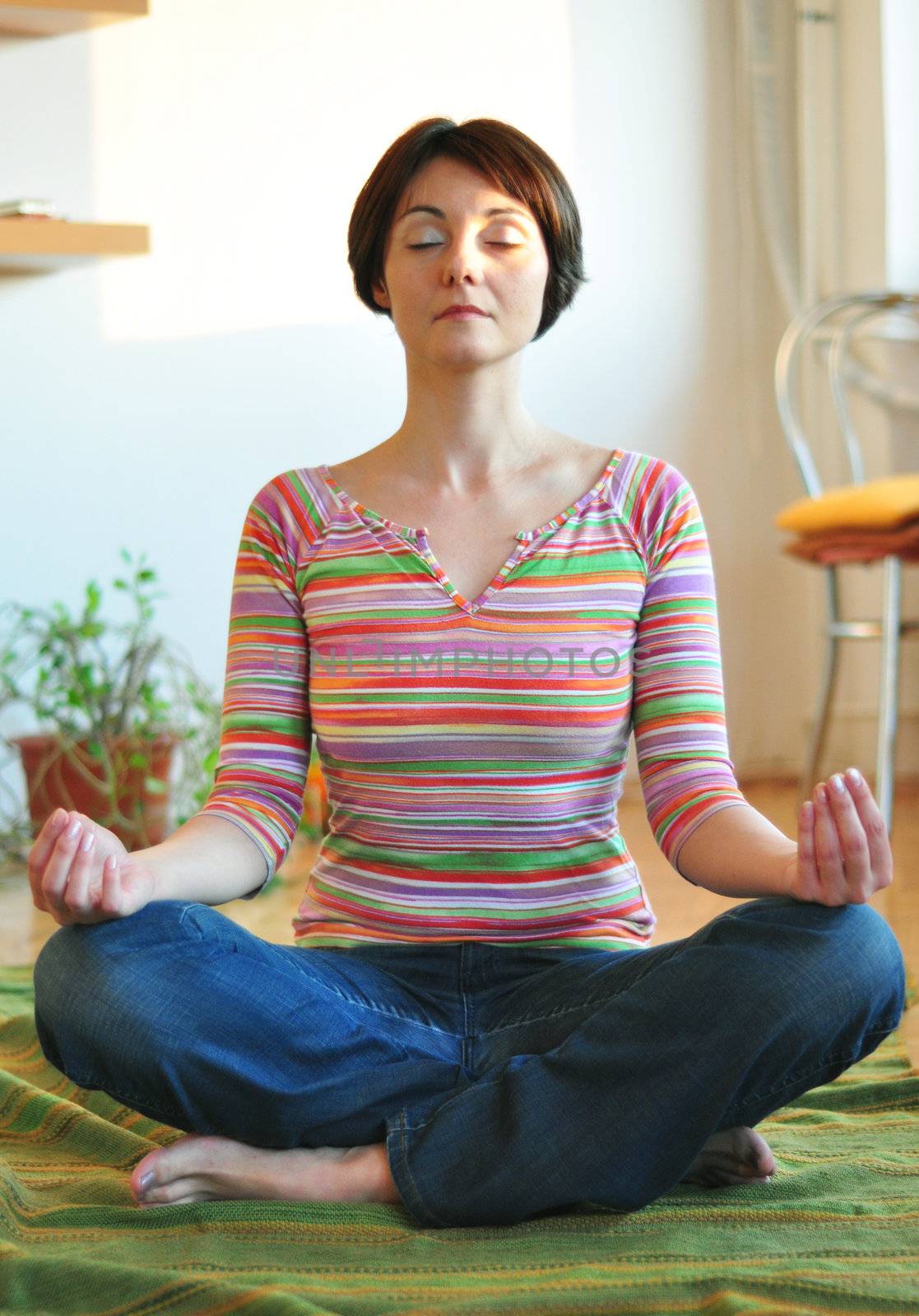 Portrait of happy young woman doing yoga on floor at home