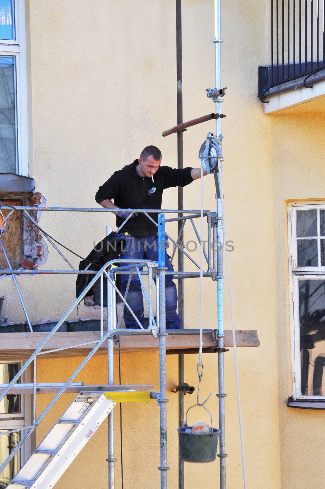 Balcony builder lowering a bucket with bricks to the ground in Stockholm, Sweden. Photo taken september 28 2011