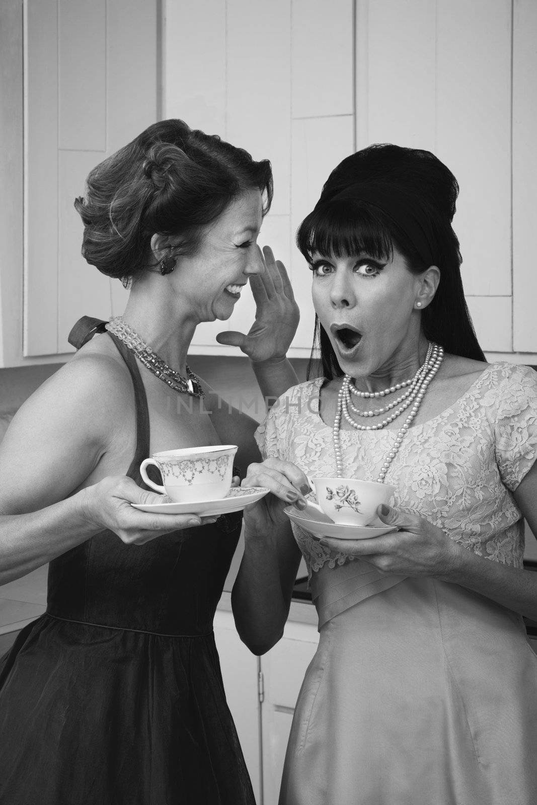 Pretty retro Caucasian women gossiping over coffee in kitchen