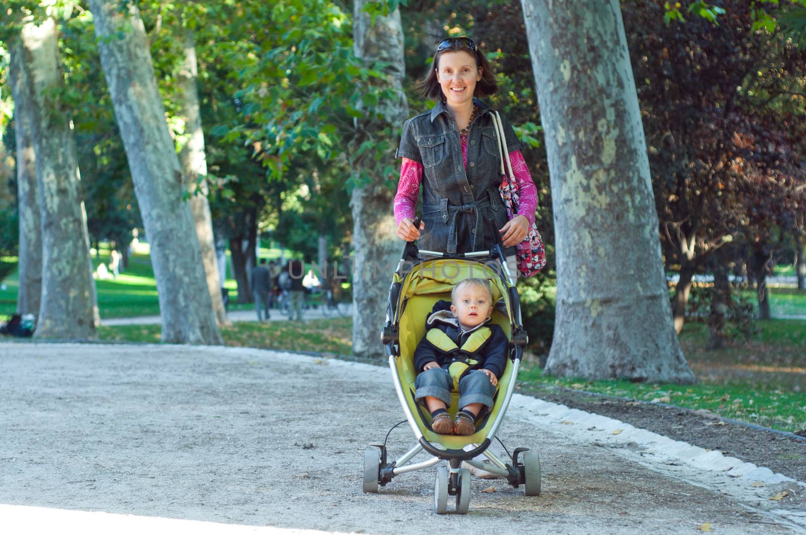 Happy mother with her son walking in the park in the sunny day