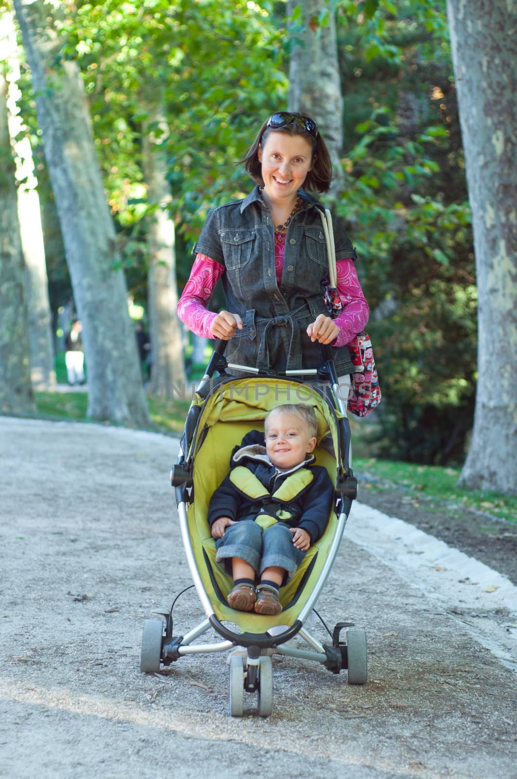 Happy mother with her son walking in the park in the sunny day