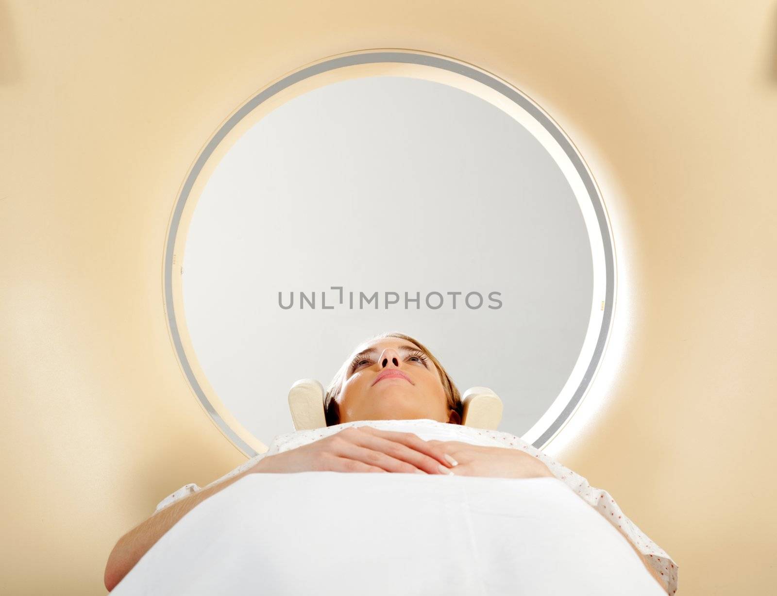 A woman laying down with eyes open having a CT scan