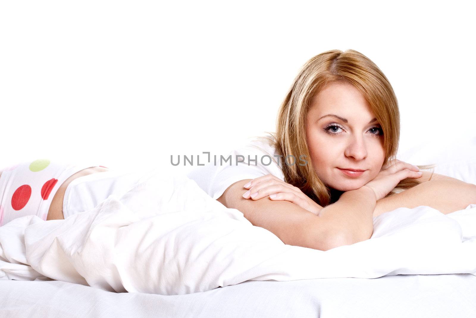 woman lying in bedroom smiling on a white background