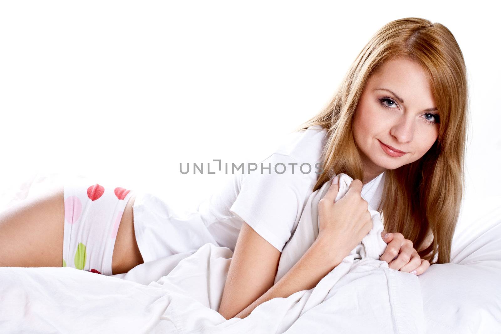 woman lying in bedroom smiling on a white background