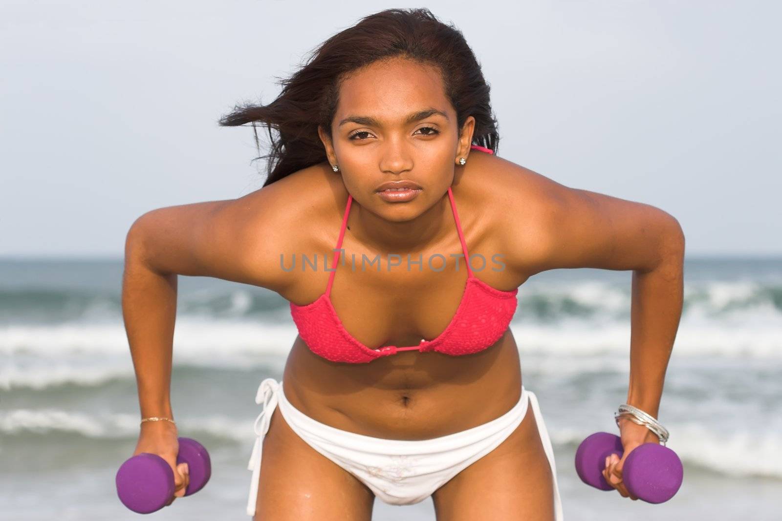 Ethnic Fitness model exercising with two dumbbells