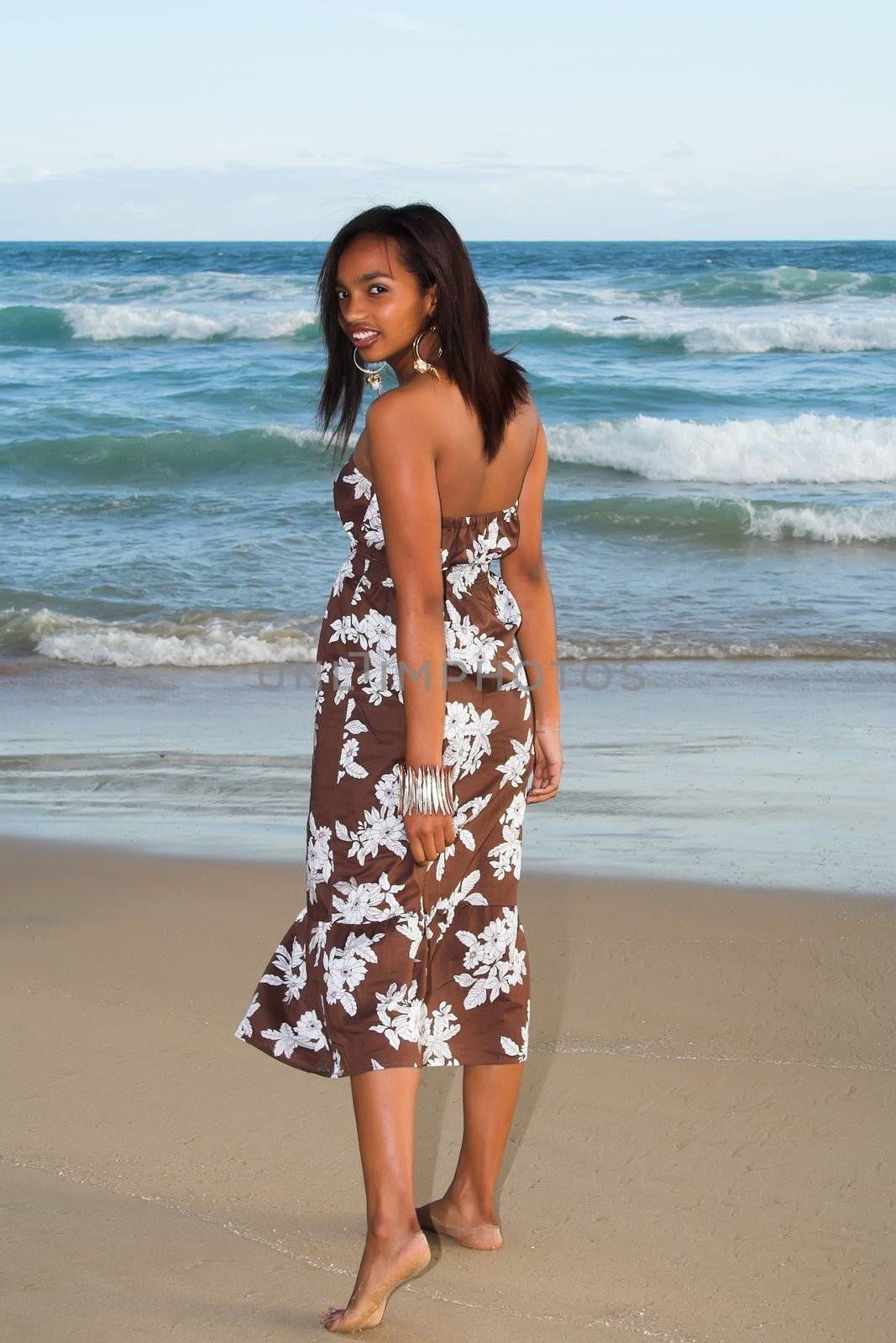 Ethnic model walking and looking back at the beach