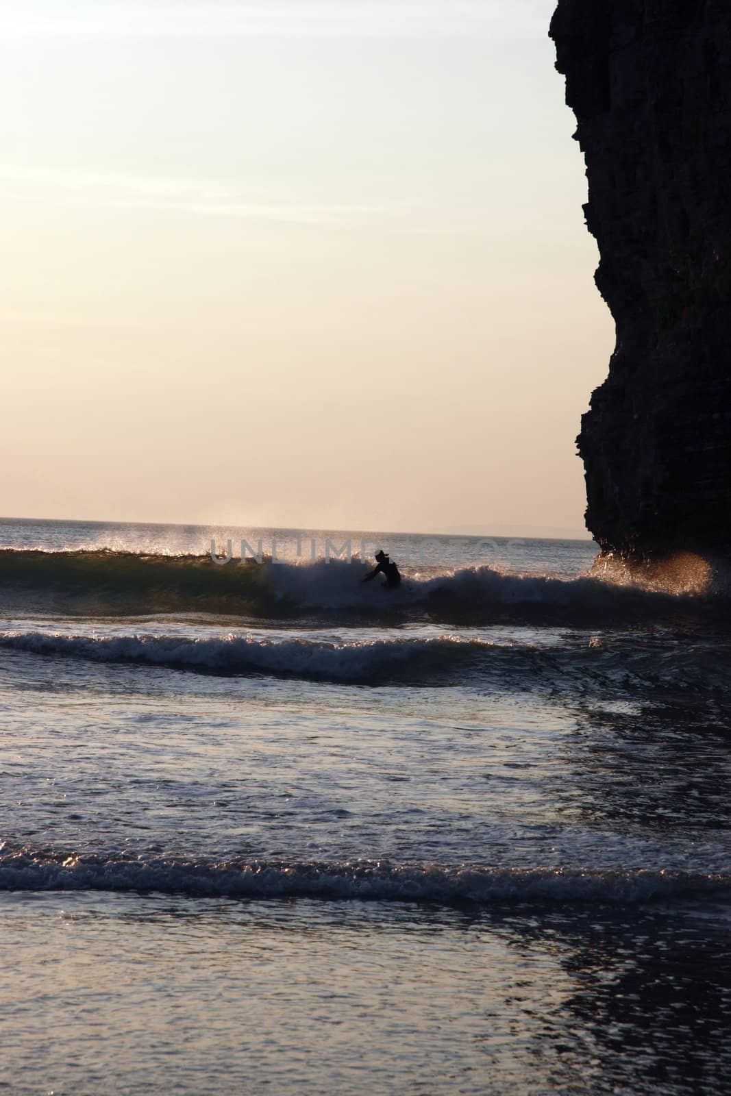 lone surfer beside the cliffs