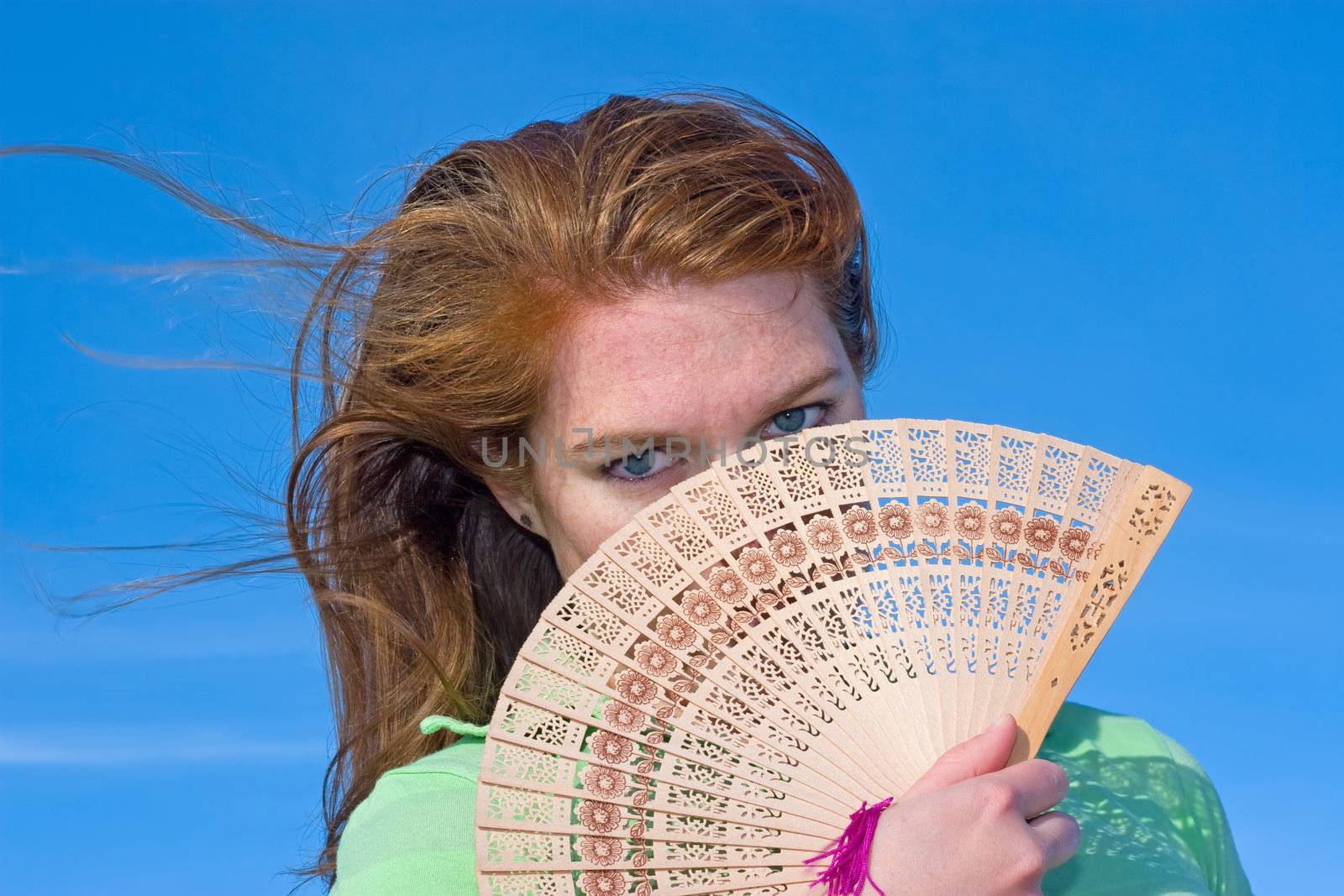 Attractive red head using an Asian fan