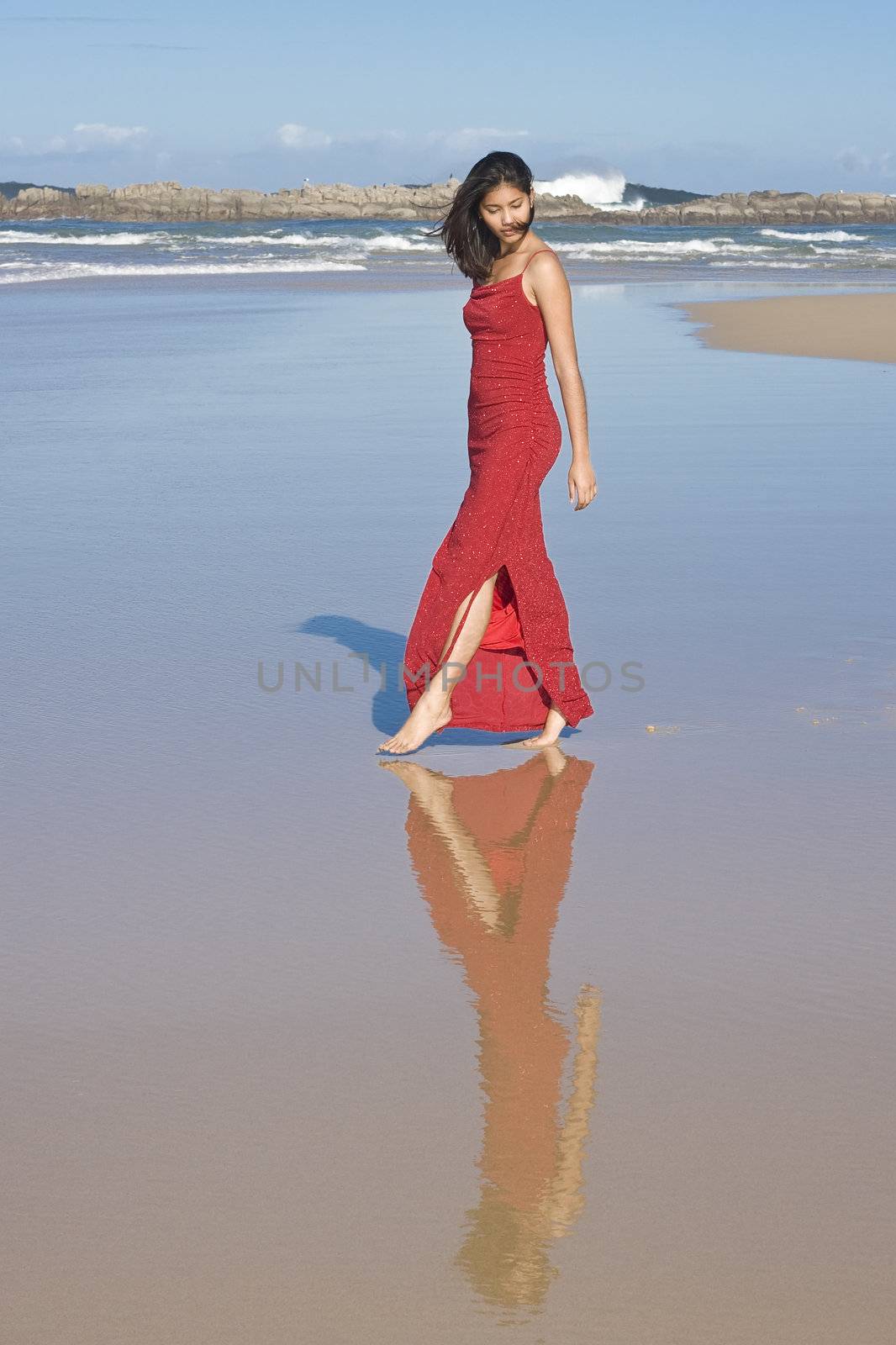 Lady in red dress walking at the beach