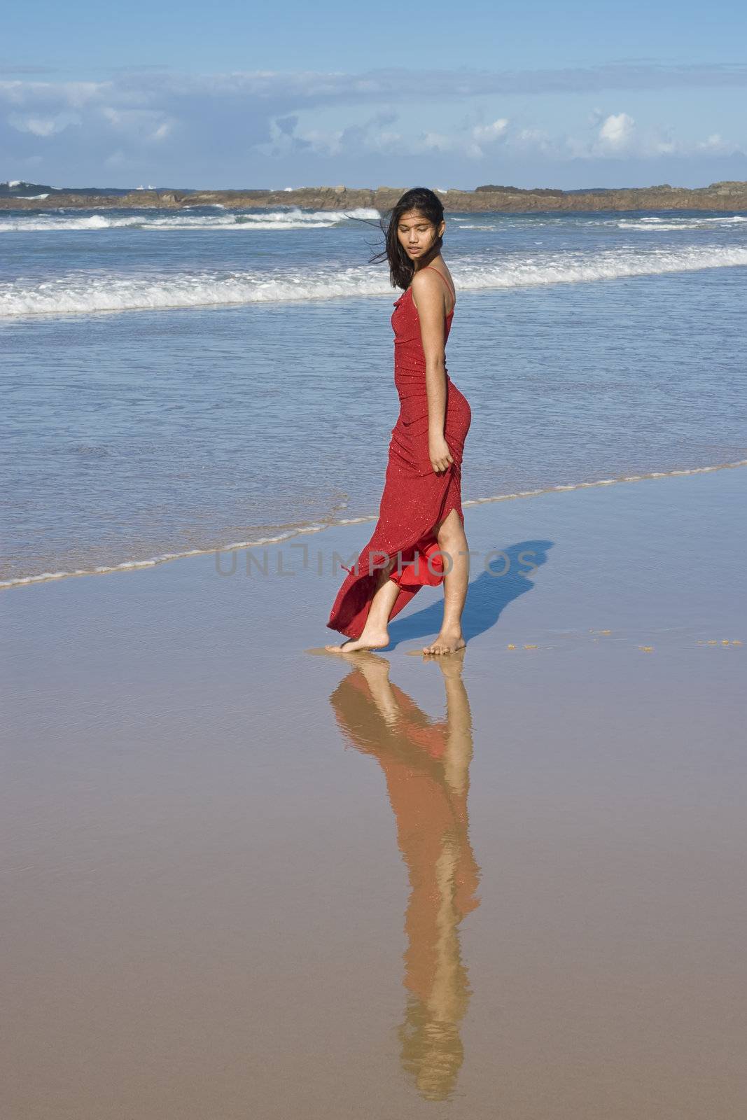 Beautiful girl in red dress on the beach