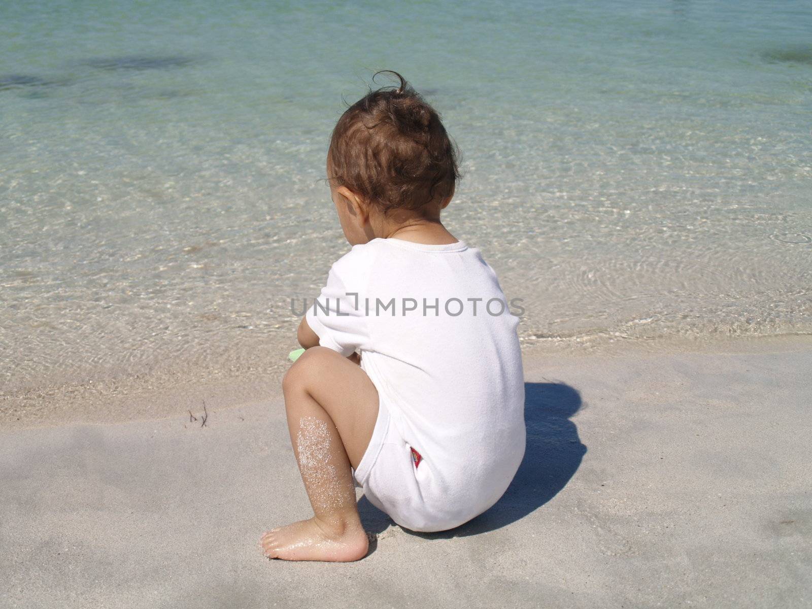 baby playing next to the ocean