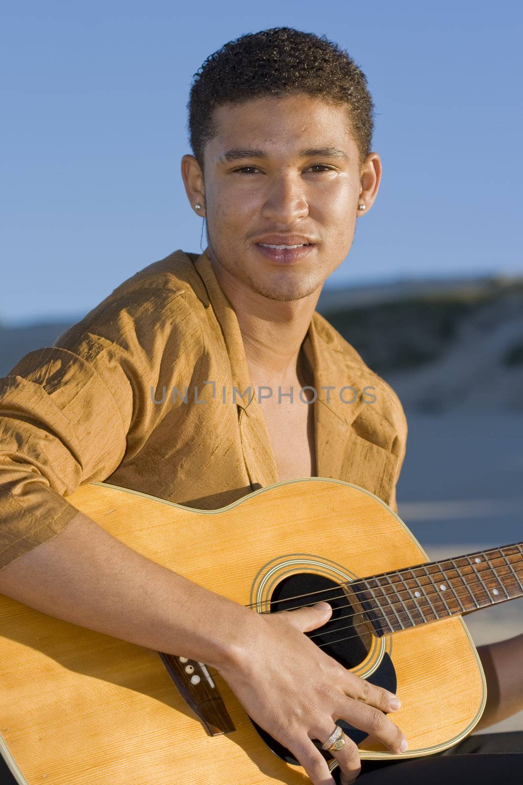 Young musician holding his guitar and looking at the camera