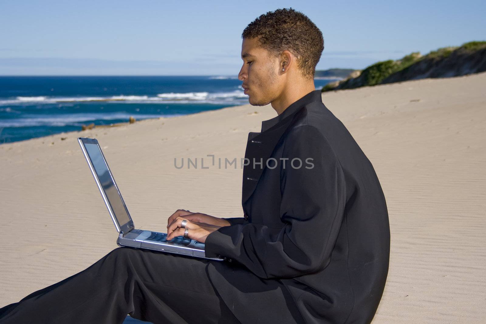 Young professional working on a laptop at the beach