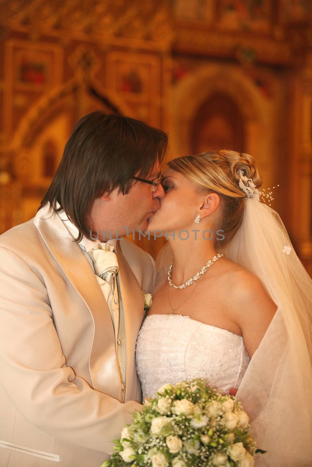 The groom and the bride kiss in church