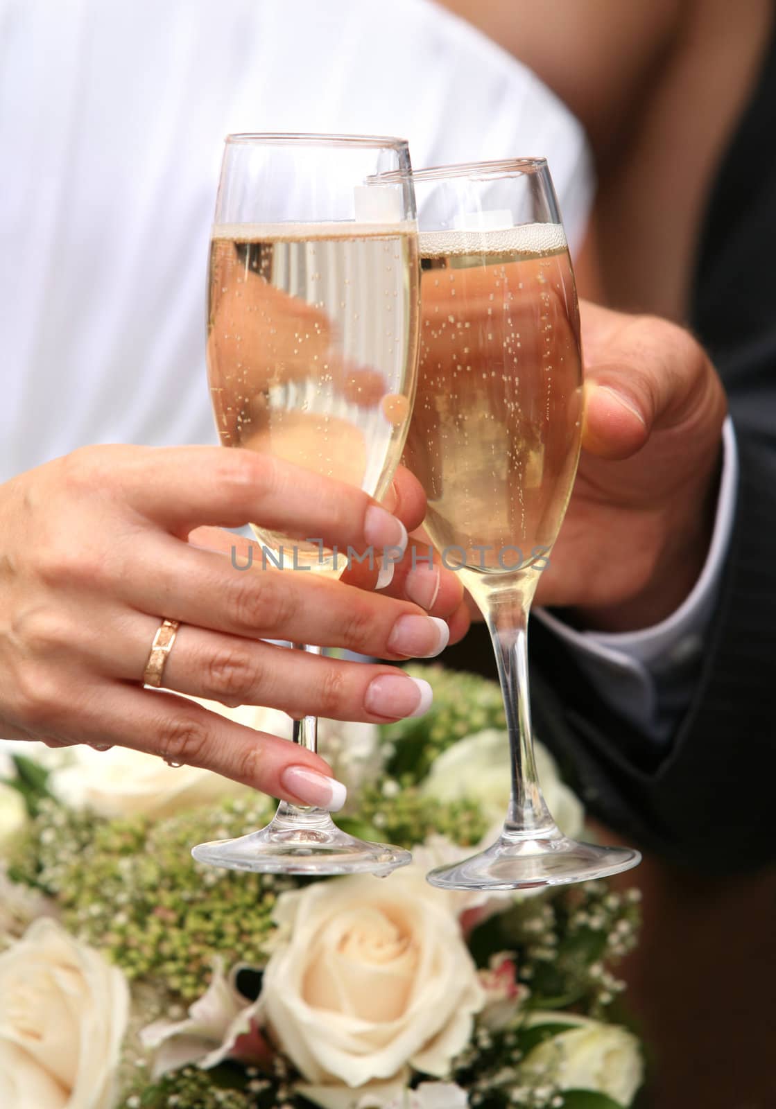 Glass of champagne in a hand of the groom and bride
