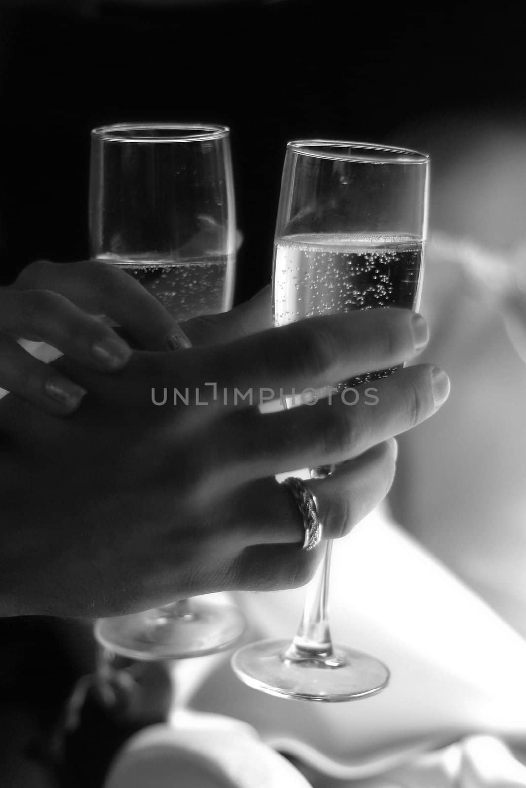 Glass of champagne in a hand of the groom and bride. b/w