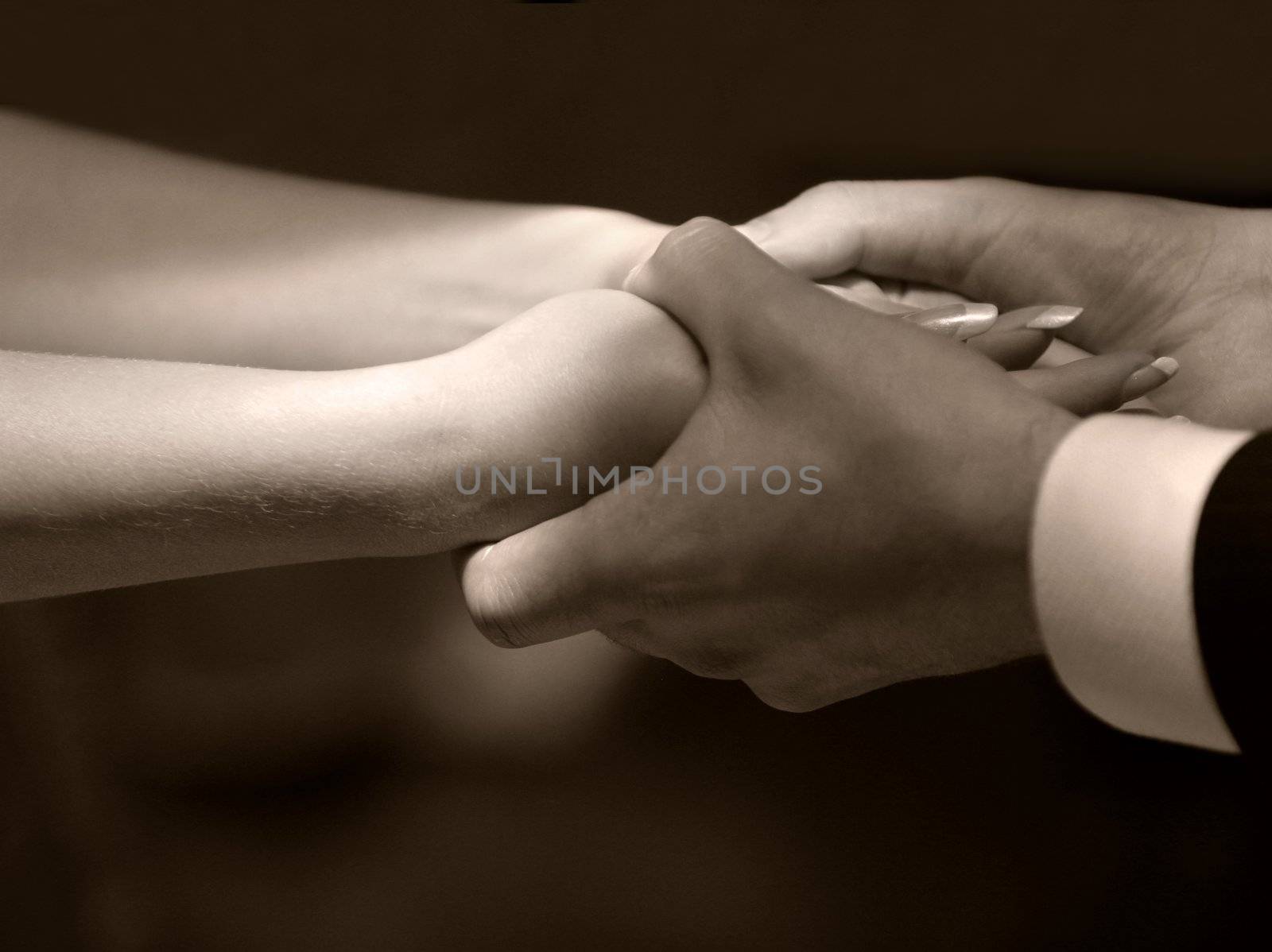 Female hands in man's hands on a dark background. b/w+sepia