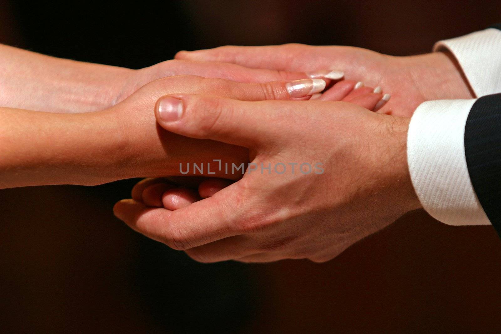 Female hands in man's hands on a dark background