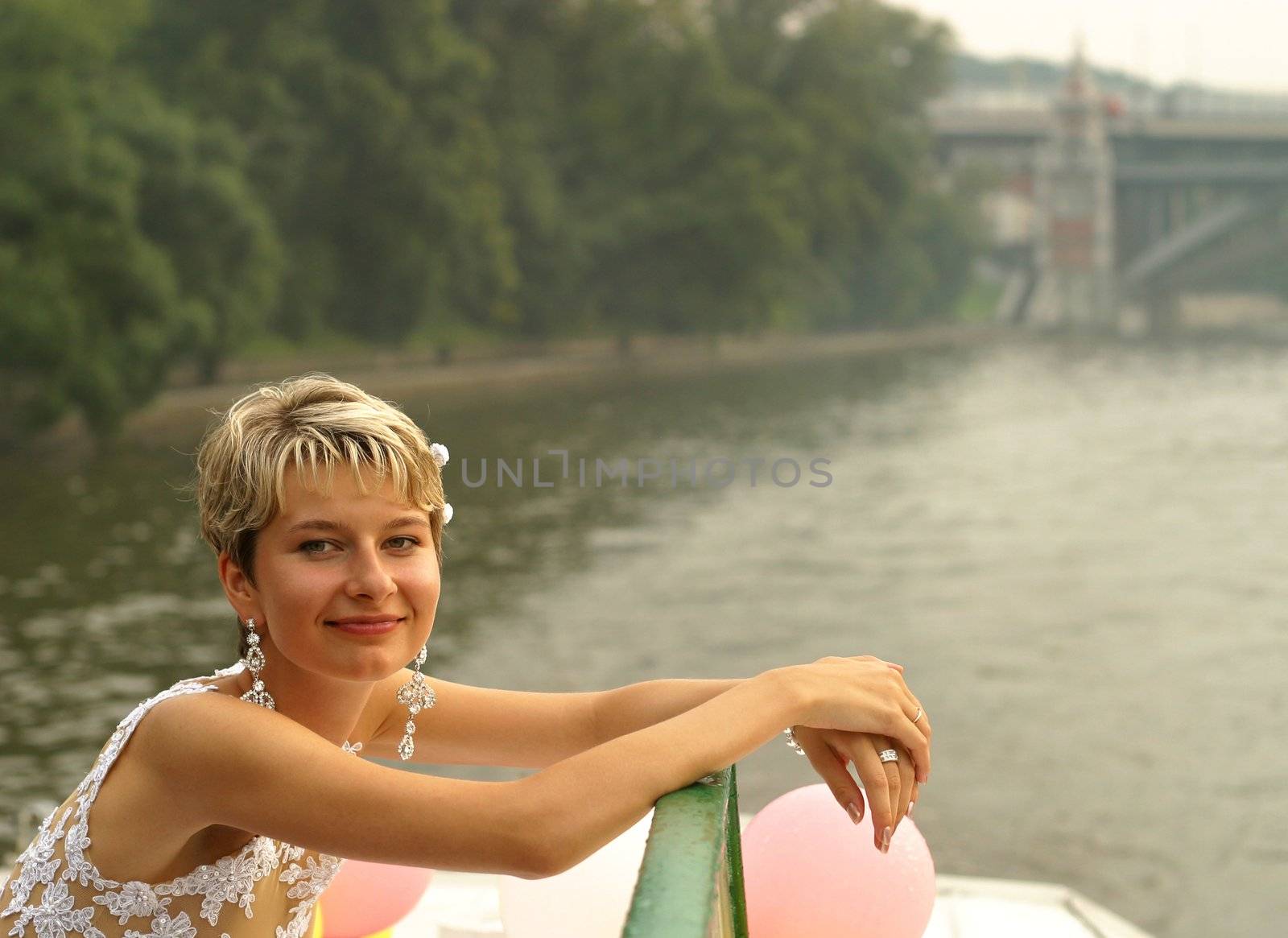 Smiling bride stands by the steam-ship
