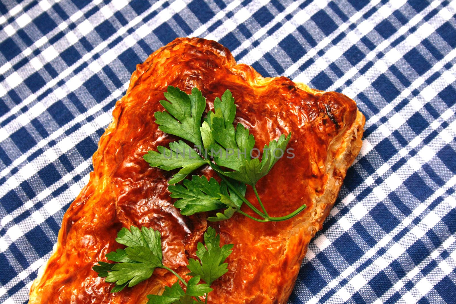 a pie from a puff test is decorated greenery of parsley on the checked serviette